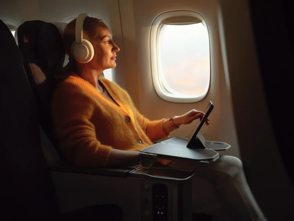 a woman sitting in an airplane with headphones on. British Airways Wi-Fi. {Tech} for Travel. https://techfortravel.co.uk