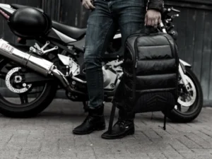 a person holding a backpack next to a motorcycle. Black Friday Deals 2025