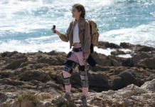 Hiking upgrade, the Ascentiz modular exoskeleton confirms 20 km range a woman standing on a rocky beach holding a camera. Ascentiz modular exoskeleton. CES 2026 News. {Tech} for Travel. https://techfortravel.co.uk