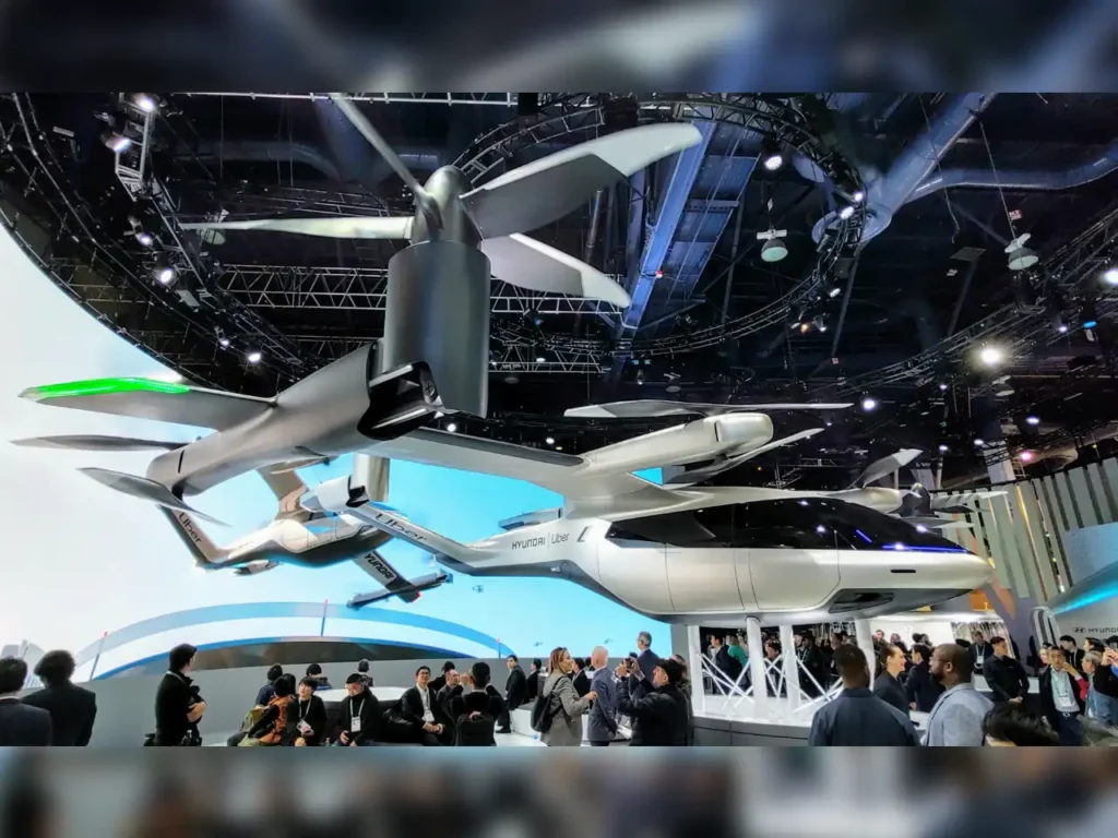 CES 2020 Uber Drone – {Tech} for Travel a group of people standing around a large white airplane. CeS 2026. {Tech} for Travel. https://techfortravel.co.uk