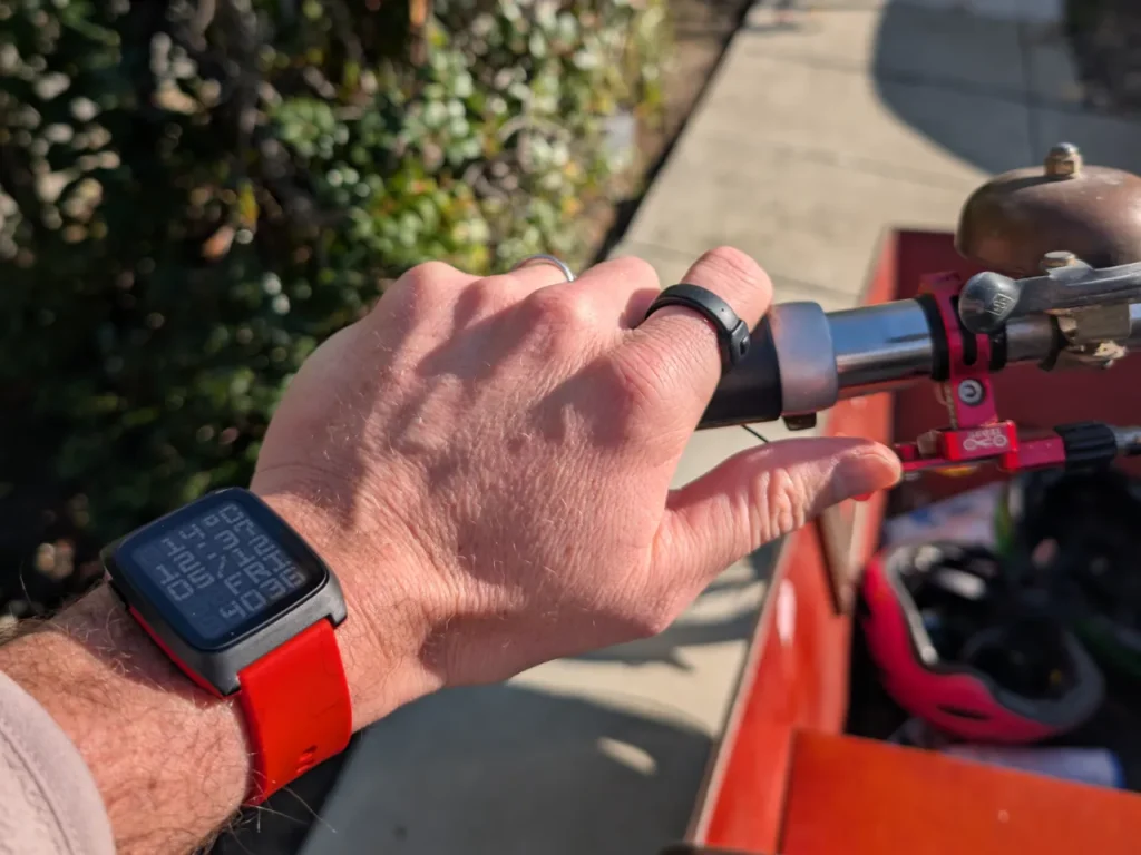 Pebble Index 01 Memory ring lifestyle 2 – {Tech} for Travel a person's hand with a watch on a bike. CES 2026 News. Pebble Index 01 Memory Ring. {Tech} for Travel. https://techfortravel.co.uk