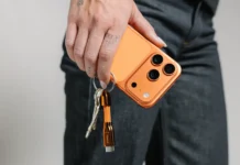 Nomad ChargeKey completes the look for Cosmic Orange iPhone owners a person holding a phone with keys. Nomad ChargeKey v2 Stellar Orange. {Tech} for Travel. https://techfortravel.co.uk