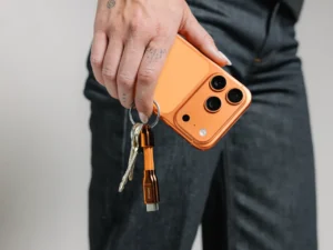 a person holding a phone with keys. Nomad ChargeKey v2 Stellar Orange. {Tech} for Travel. https://techfortravel.co.uk