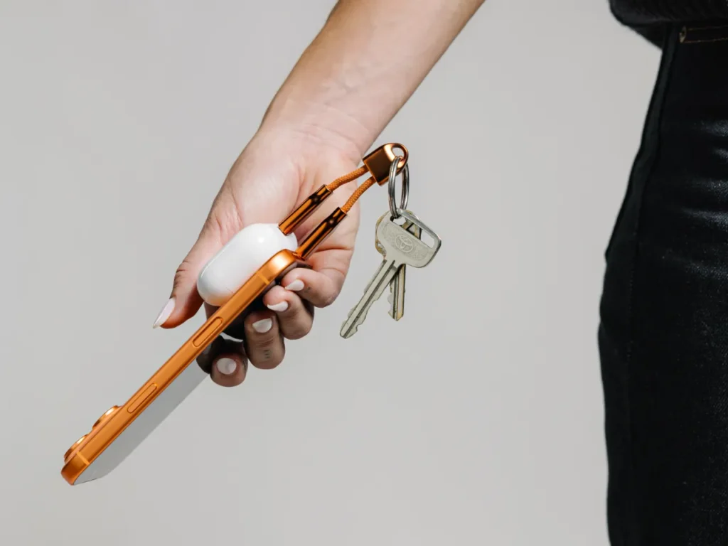 a hand holding a key chain. Nomad ChargeKey V2 Stellar Orange. {Tech} for Travel. https://techfortravel.co.uk