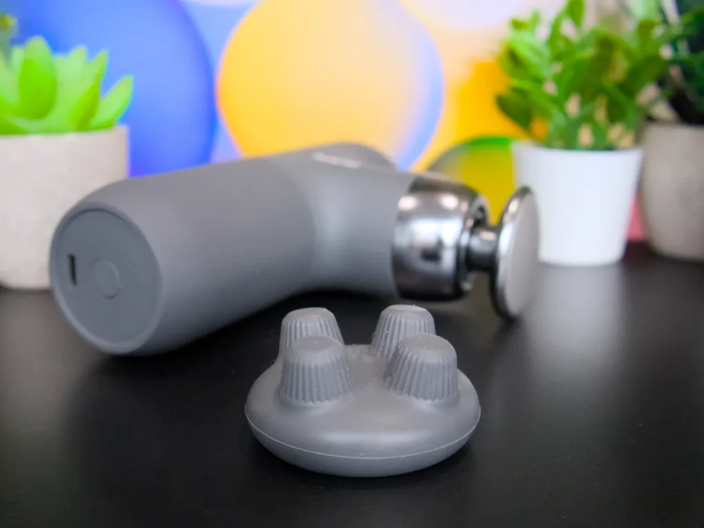 a grey device with a round object on a black surface. RENPHO Mini Thermal Massage Gun review. {Tech} for Travel. https://techfortravel.co.uk
