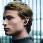 a man with earbuds in his ear. Sony WF-1000XM6 Earbuds. {Tech} for Travel. https://techfortravel.co.uk