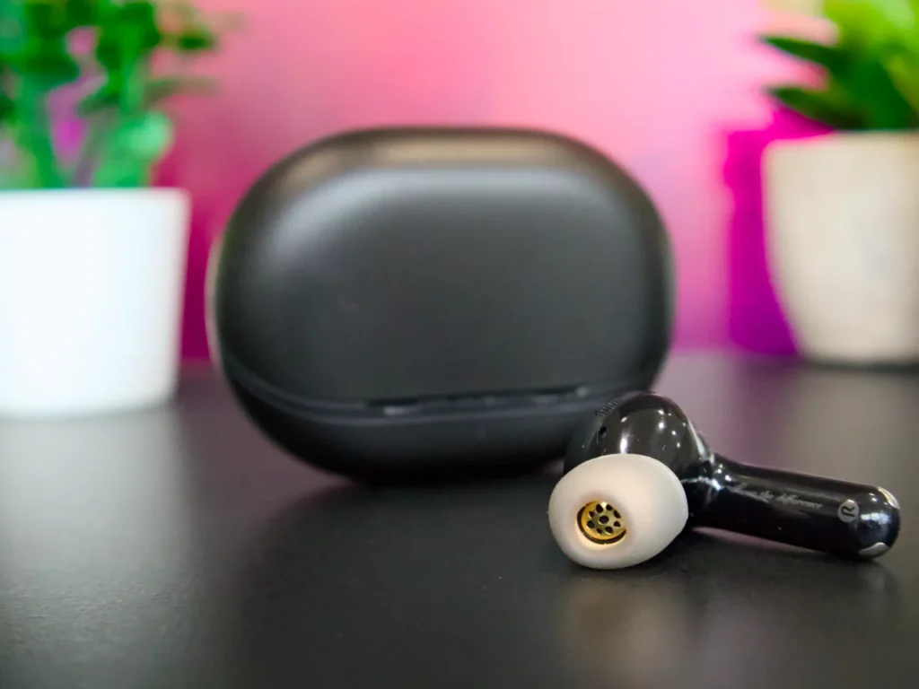 a black earbuds on a black surface. SoundPEATS Air5 Pro Plus Review. {Tech} for Travel. https://techfortravel.co.uk